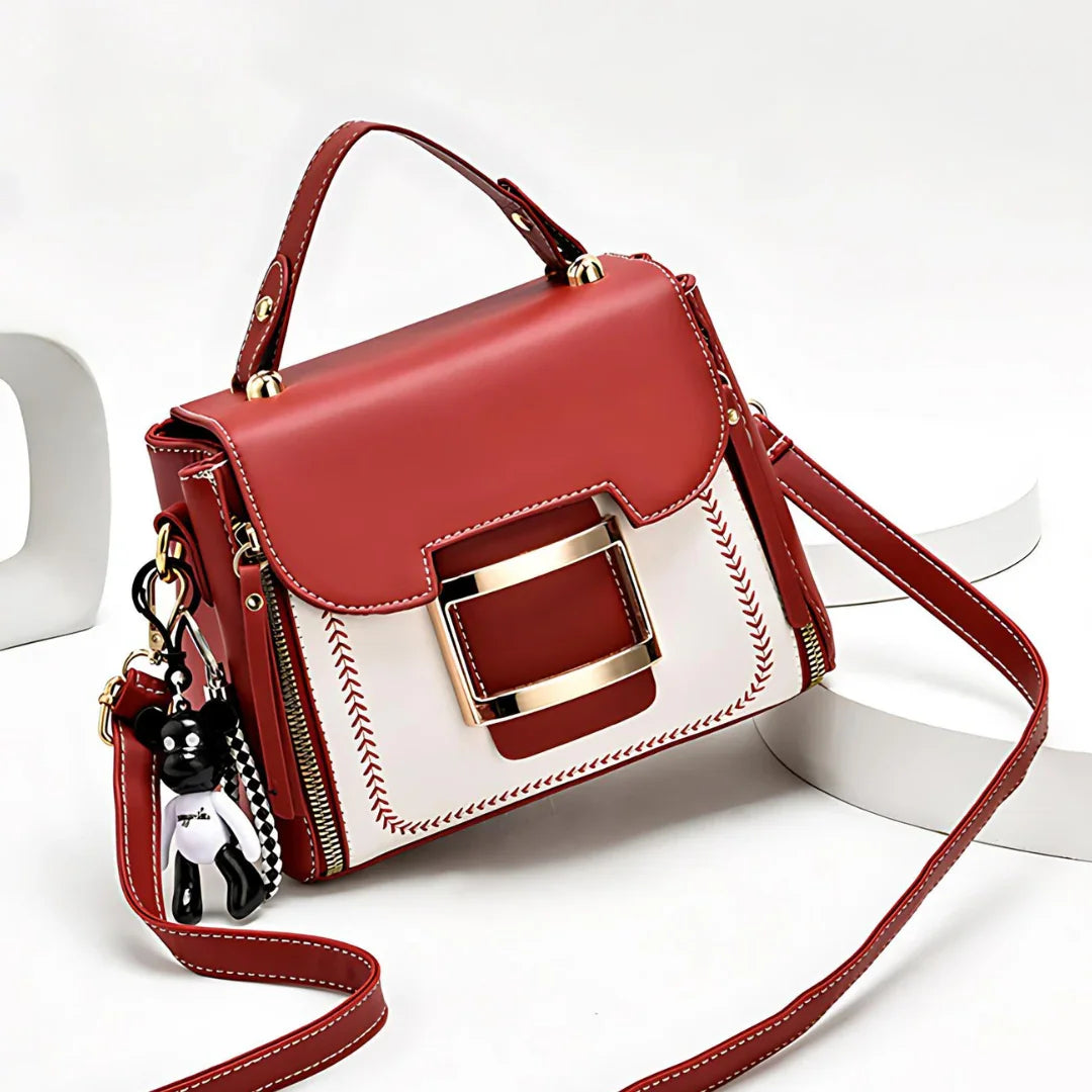 Red and white leather handbag with gold buckle, top handle, and bear keychain charm