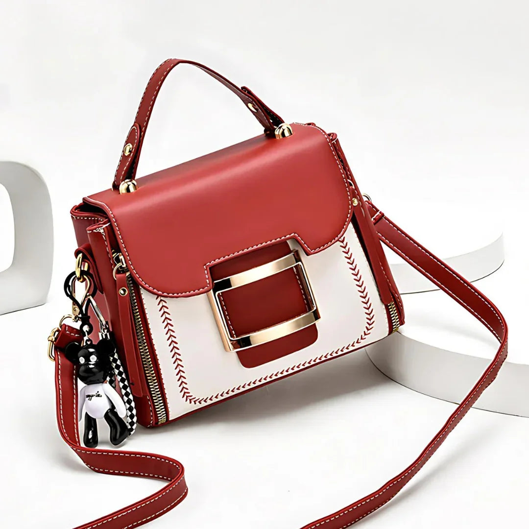 Red and white leather handbag with gold buckle, top handle, and bear keychain charm