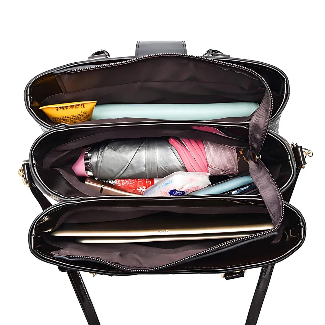 Top view of organized black tote bag filled with laptop, umbrella and daily essentials