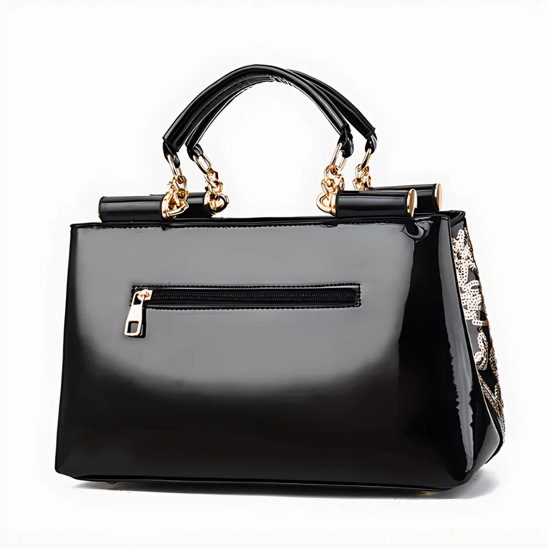 Glossy black handbag with gold chain handles and side floral sequin detail, front zipper