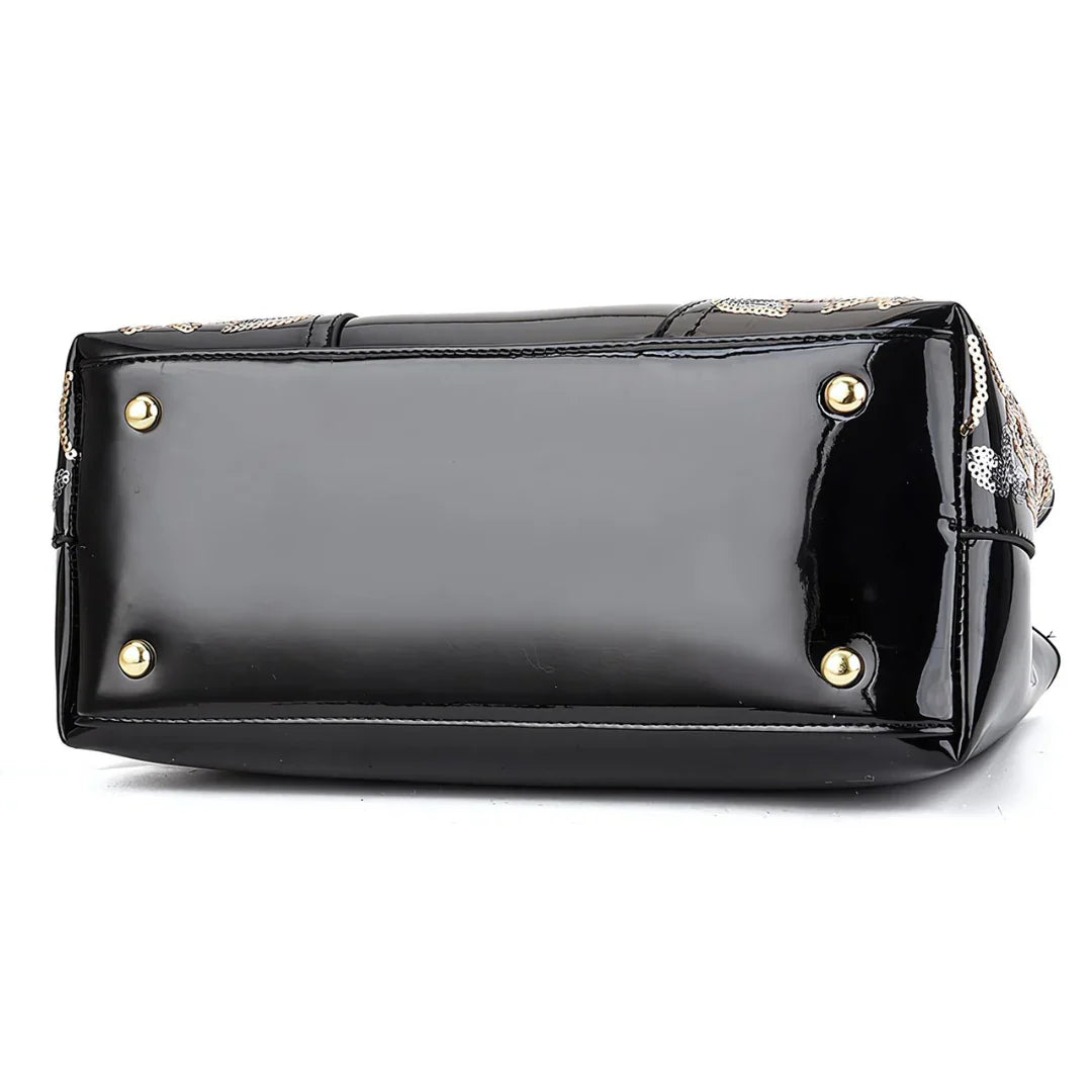 Black patent leather handbag bottom with gold metal feet, white background