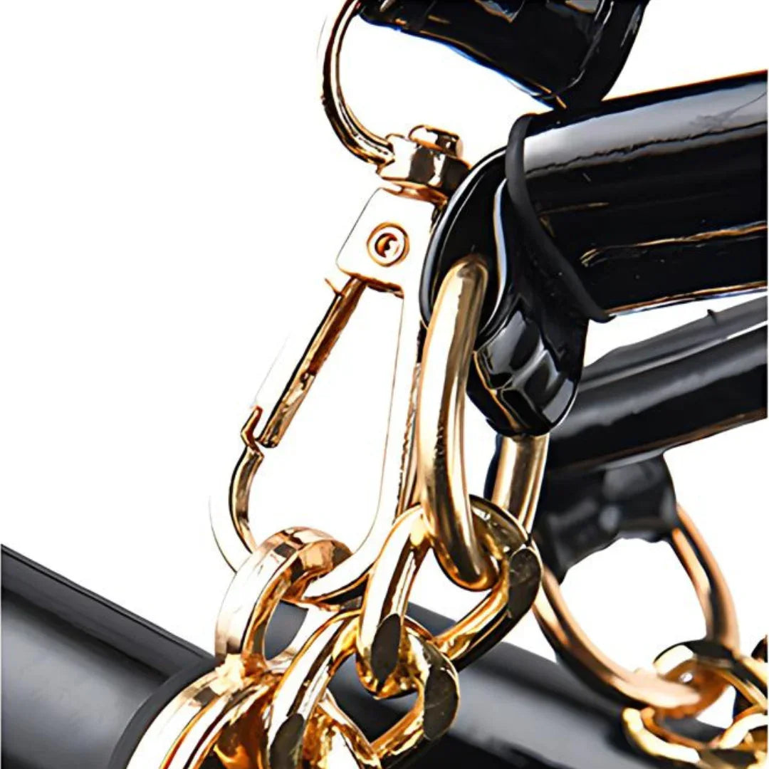 Close-up of gold chain and black patent leather handbag strap hardware