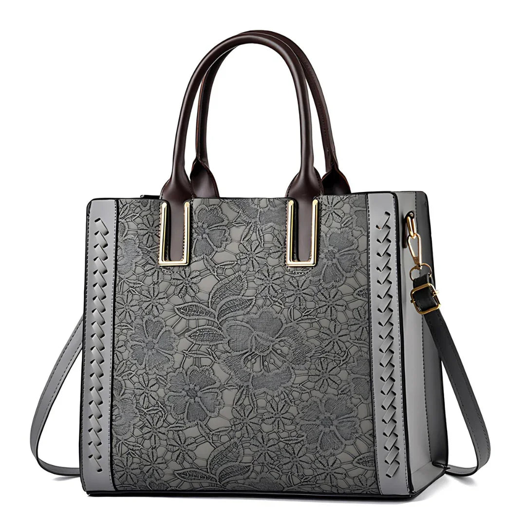 Gray floral embossed leather tote bag with dark brown handles and crossbody strap