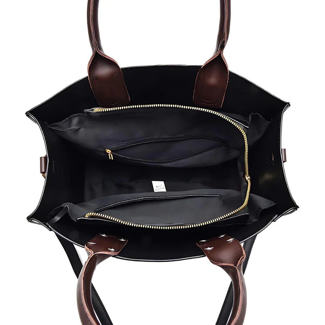 Open black tote bag with brown leather handles and gold zipper pockets