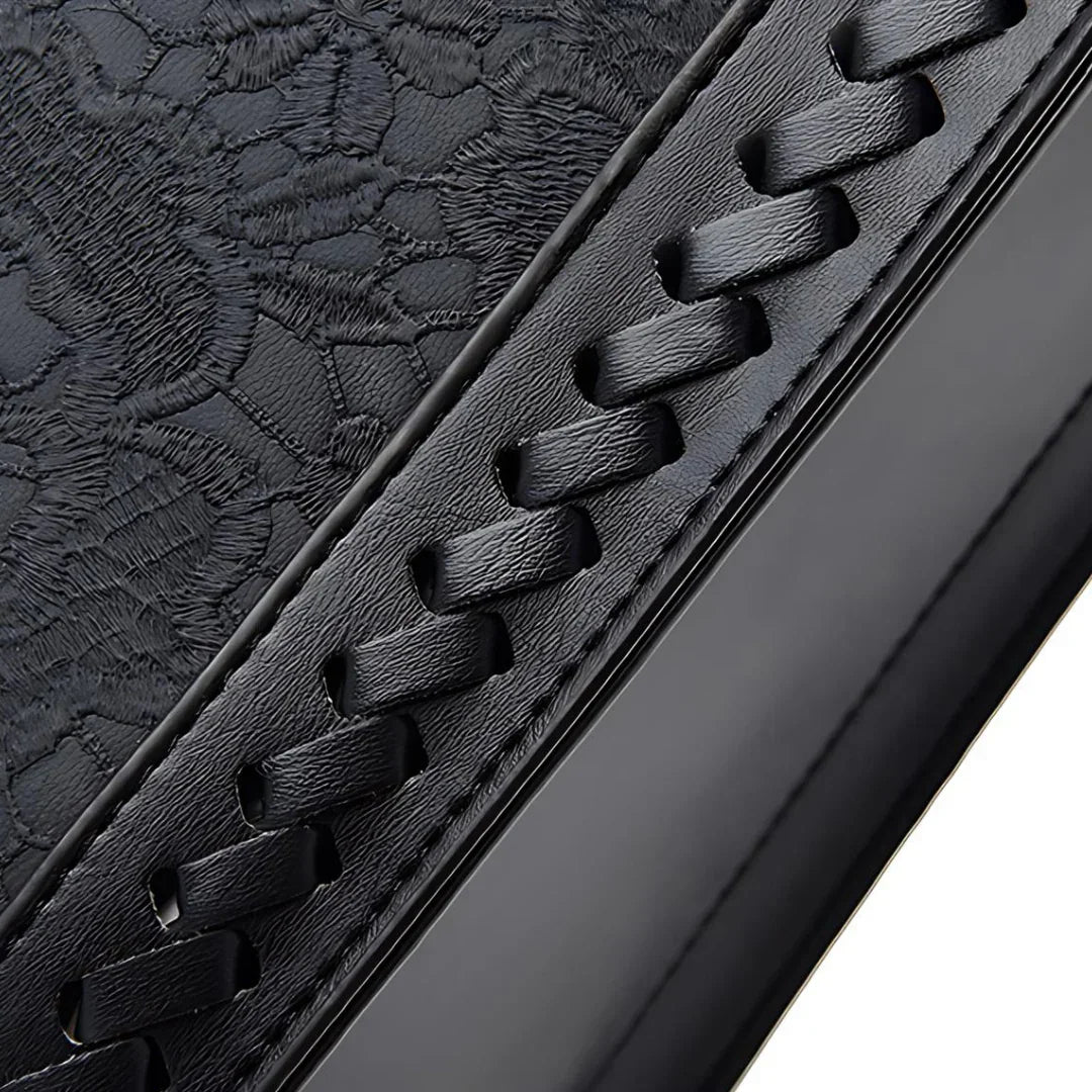 Black leather with embossed floral pattern and woven stitched detail, close-up