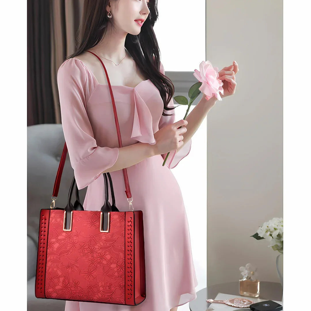 Woman in pink dress holding pink flower and red floral handbag indoors