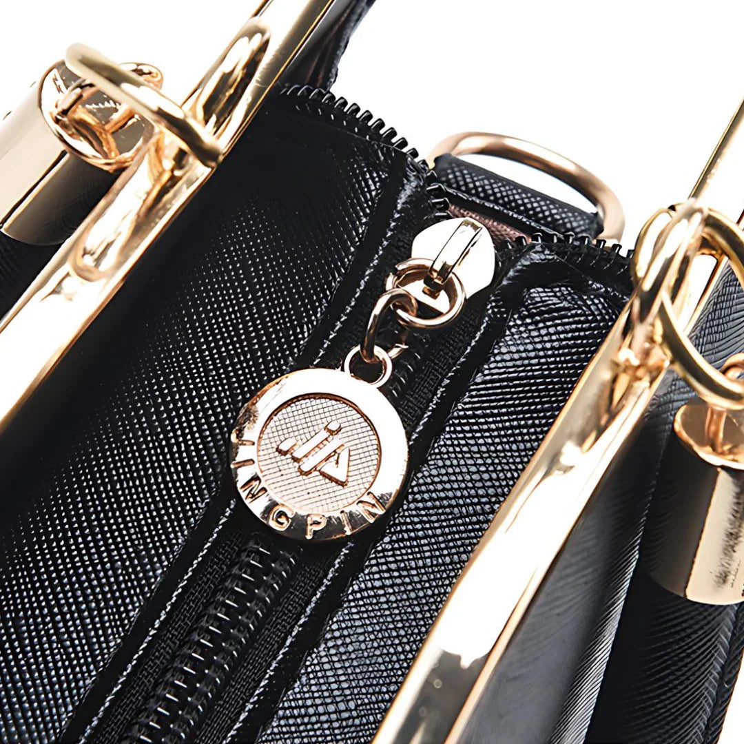 Black textured handbag with gold zipper and metallic charm detail