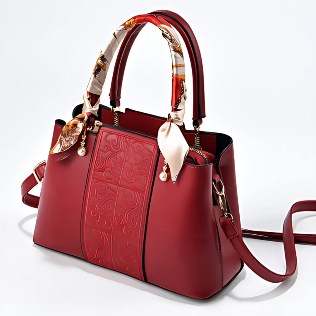 Elegant red leather handbag with embossed pattern, scarf-wrapped handles, gold hardware
