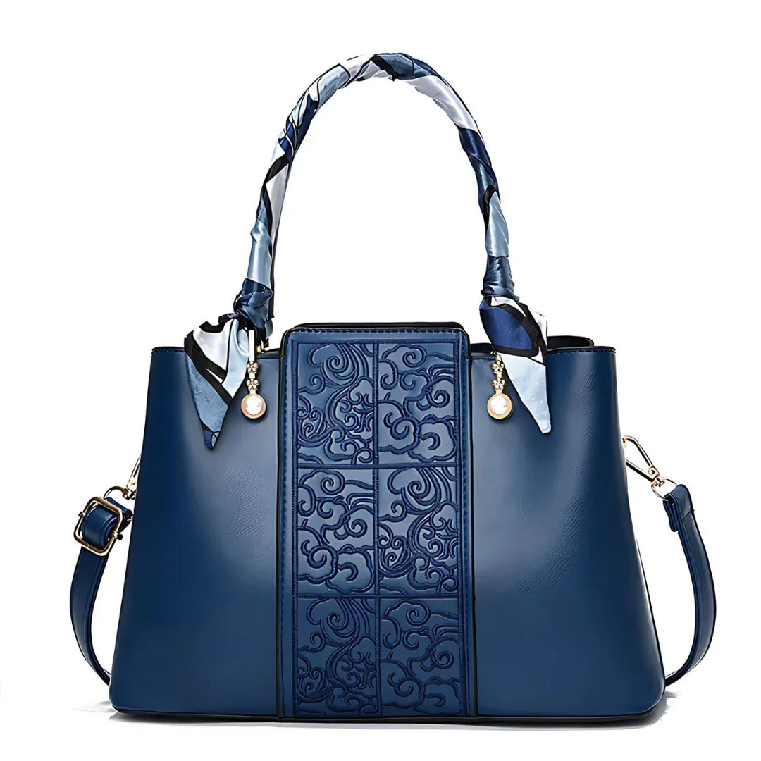 Elegant blue leather handbag with embossed pattern, scarf-wrapped handle, and gold accents