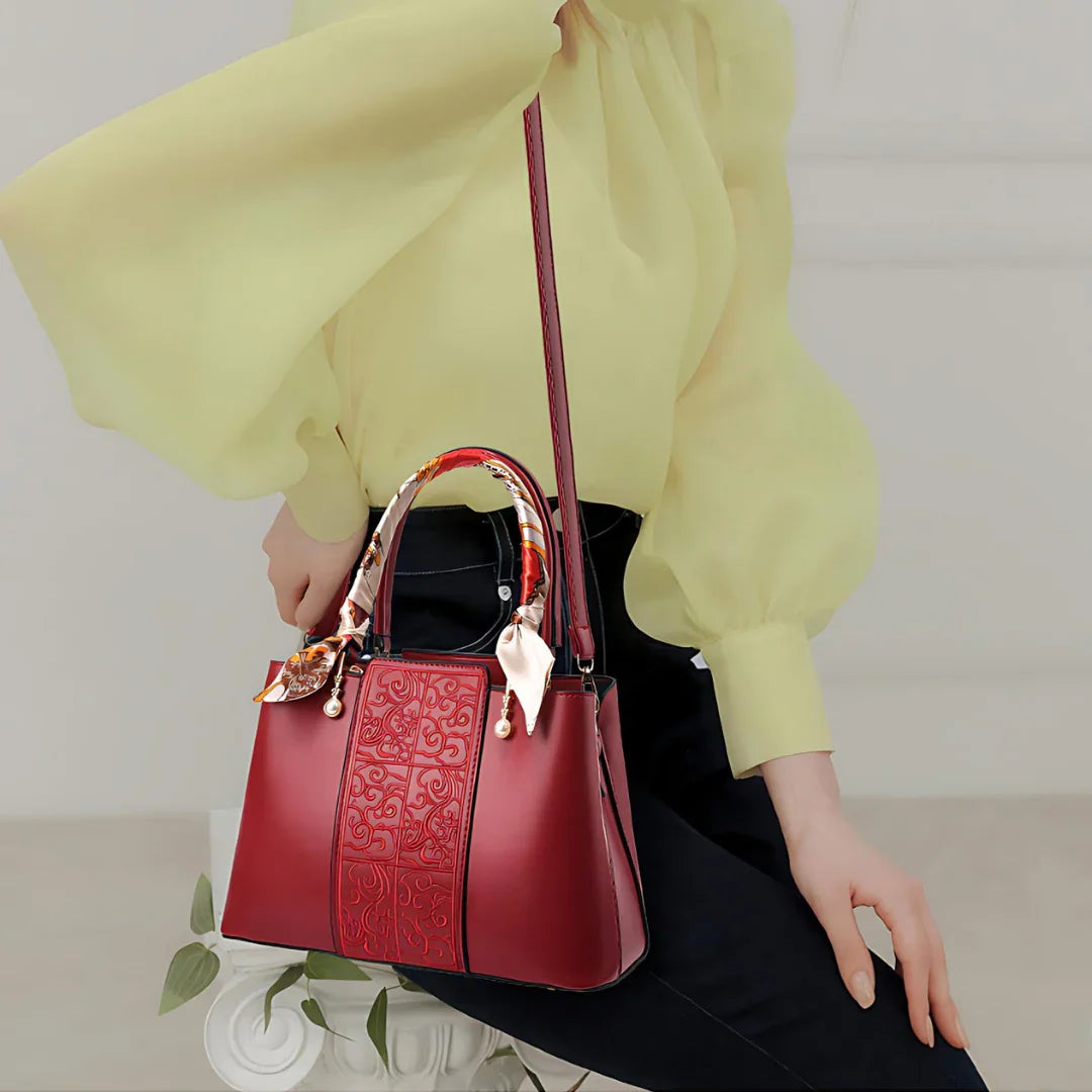Elegant woman in yellow blouse holding red embossed leather handbag with scarf handles