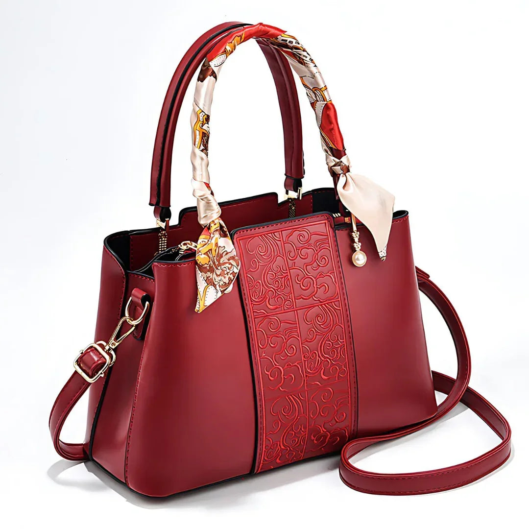 Elegant red leather handbag with embossed pattern, colorful silk handle wraps, gold accents