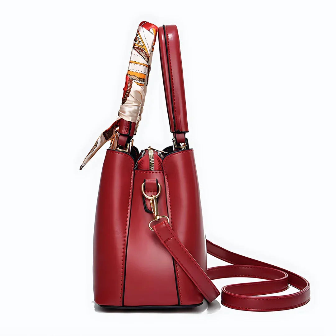 Red leather handbag with gold hardware and a patterned scarf handle, side view
