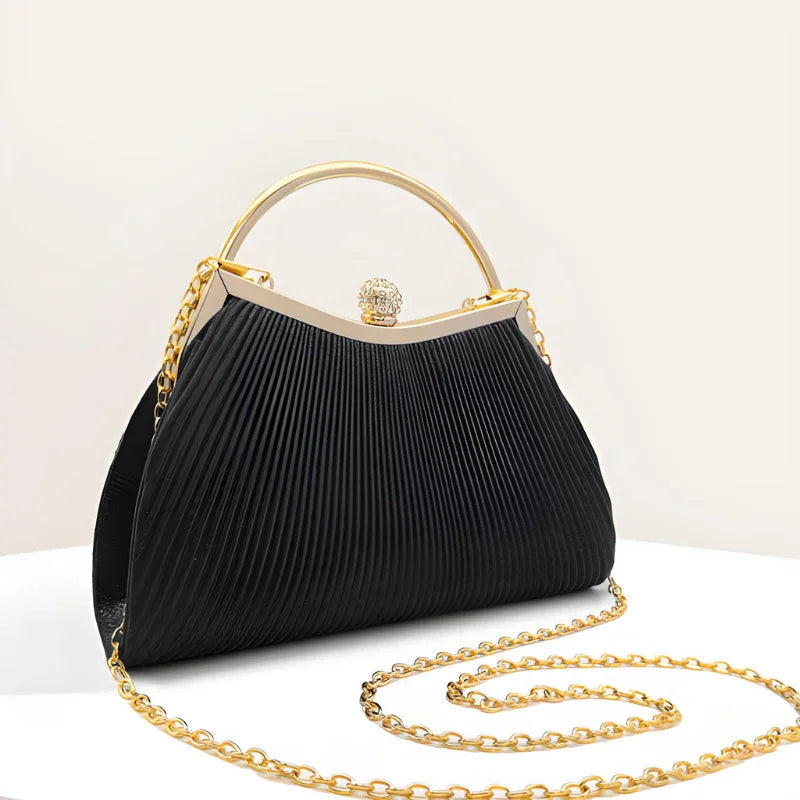 Elegant black pleated handbag with gold handle and chain on a white background