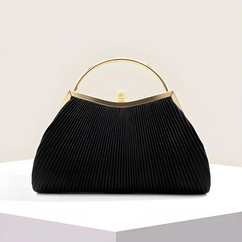 Elegant black pleated handbag with gold handle and clasp on a white display pedestal