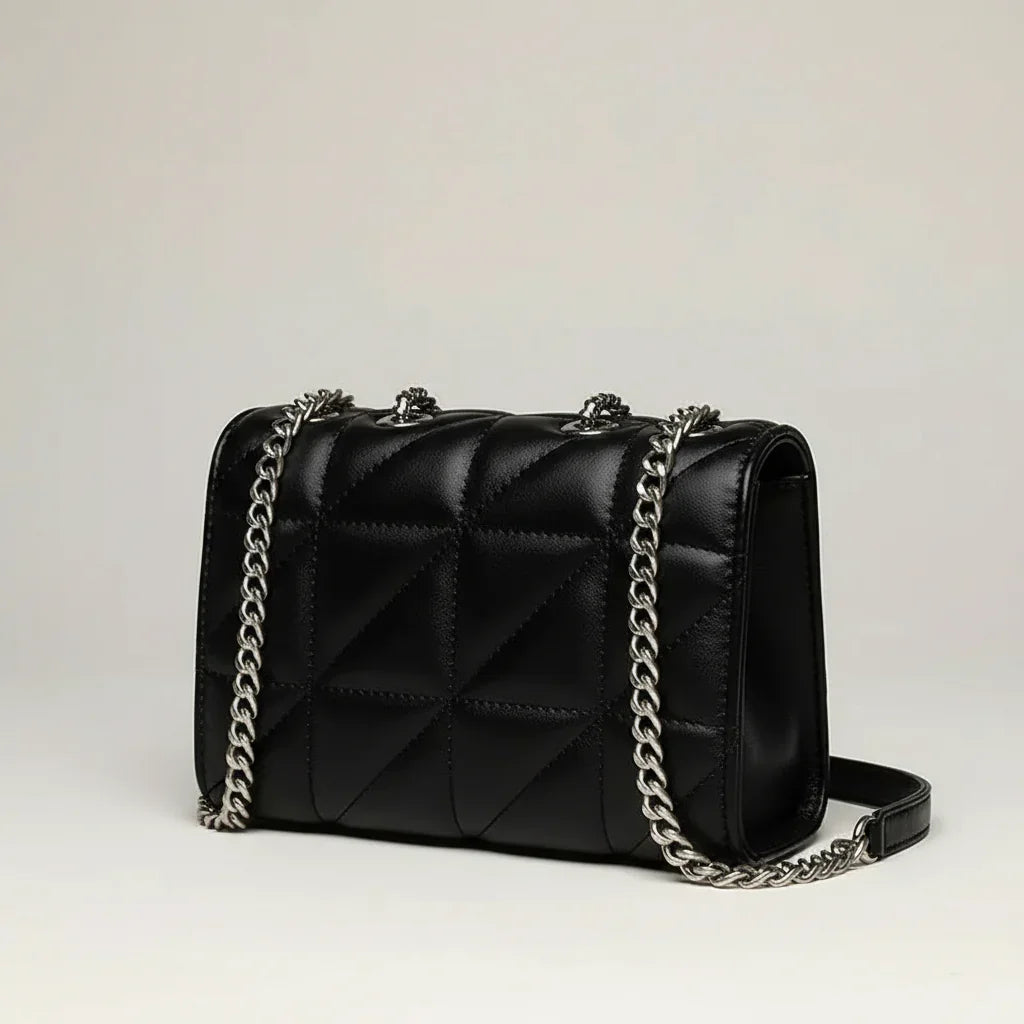 Black quilted leather shoulder bag with silver chain strap on light background