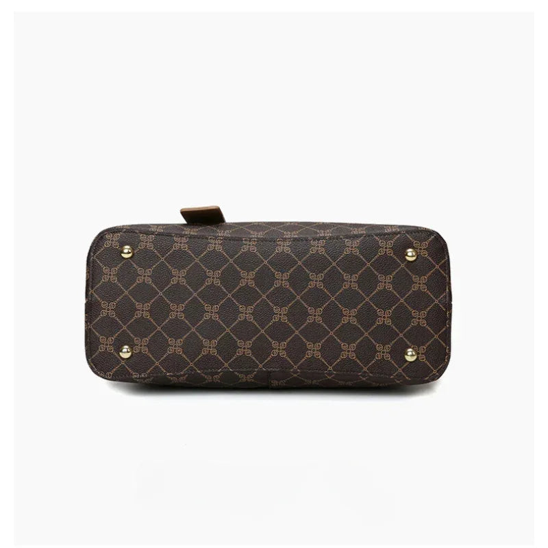 Bottom view of brown patterned leather handbag with gold feet on white background