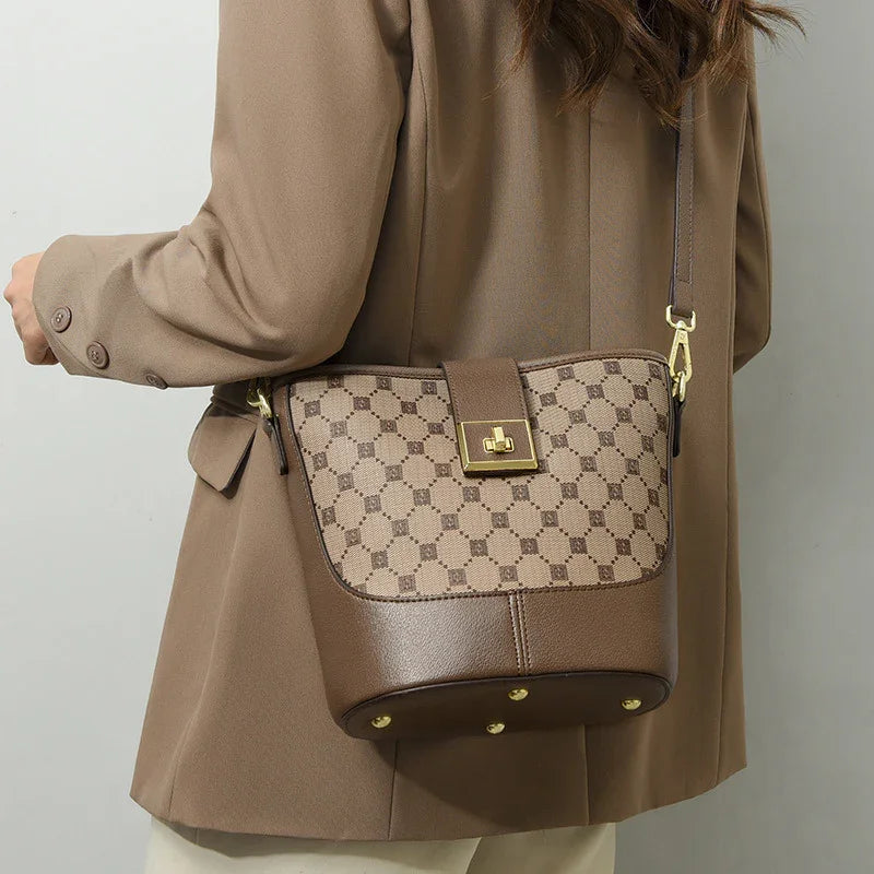 Woman wearing brown geometric bucket bag with gold hardware and crossbody strap