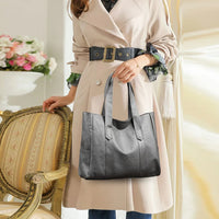 Woman in beige trench coat holding black leather tote bag in elegant room