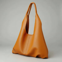 Minimalist brown leather tote bag with wide handles on neutral background