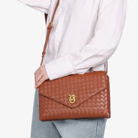 Woman wearing white shirt and jeans with brown woven leather crossbody bag