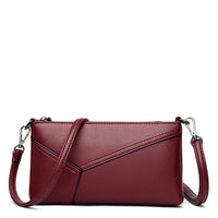 Burgundy leather crossbody purse with geometric stitching and removable strap on white background