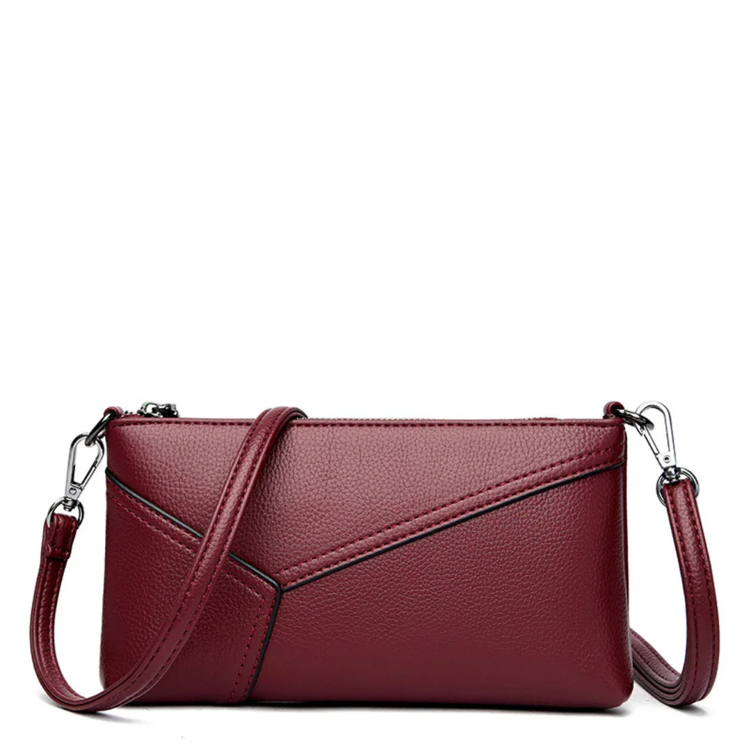 Burgundy leather crossbody purse with geometric stitching and removable strap on white background