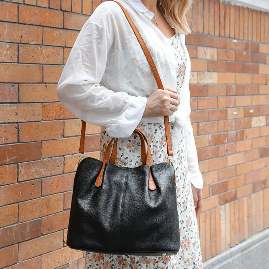 Woman in floral dress and white blouse carrying black leather tote bag with brown straps