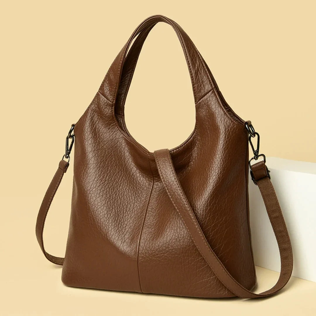 Brown leather shoulder bag with detachable strap on beige background