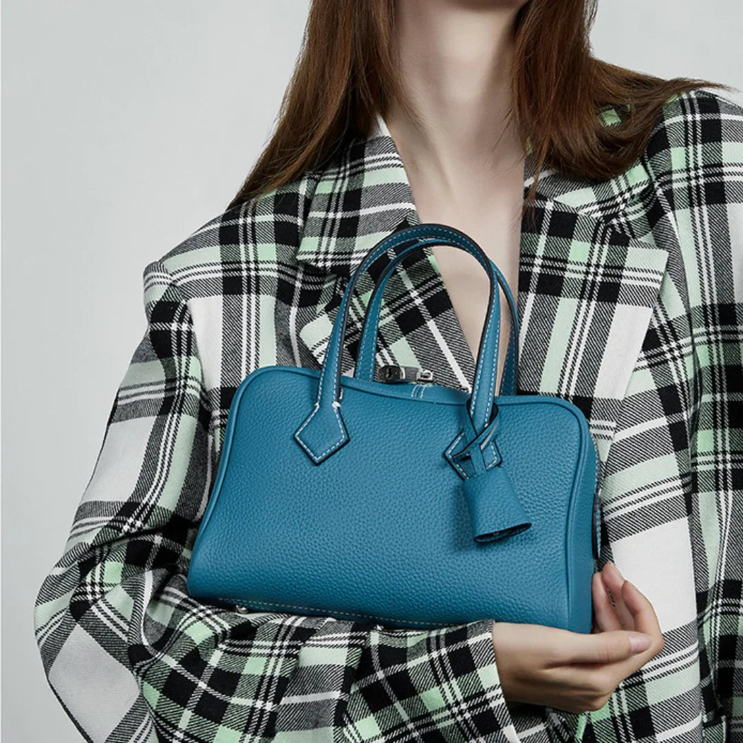 Woman in plaid blazer holding blue leather handbag