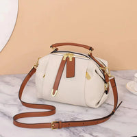 White leather handbag with brown straps and gold hardware on marble surface