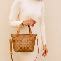 Woman in cream ribbed dress holding tan designer handbag with geometric pattern