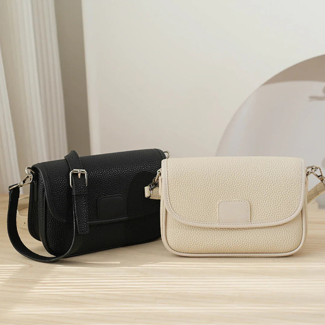Black and beige leather crossbody bags on a light wooden surface