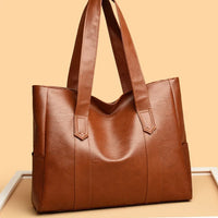 Brown leather tote bag with double handles on peach background