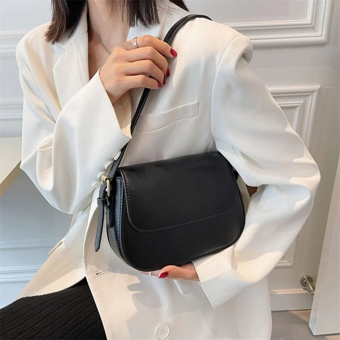 Woman in white blazer holding black leather shoulder bag