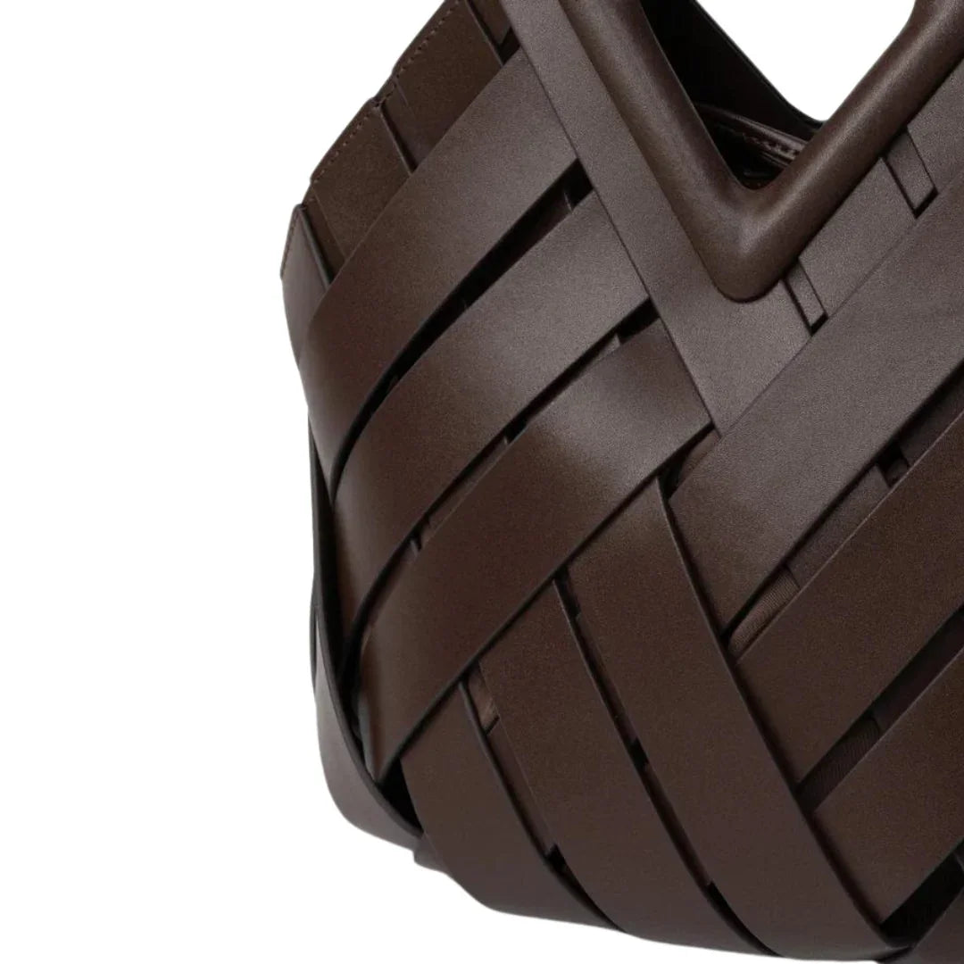 Close-up of brown woven leather handbag with geometric pattern and structured handle