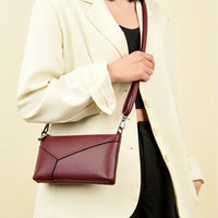 Woman in cream blazer carrying a burgundy leather crossbody purse