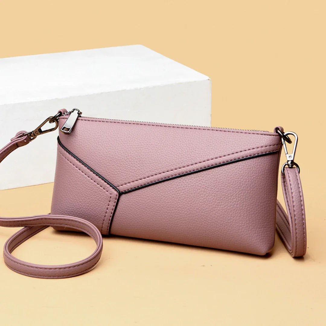 Pink leather crossbody purse with geometric stitching on beige background