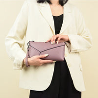Woman in cream blazer holding a purple leather wristlet clutch bag
