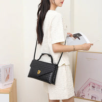 Woman in textured cream outfit holding magazine, wearing black woven leather shoulder bag