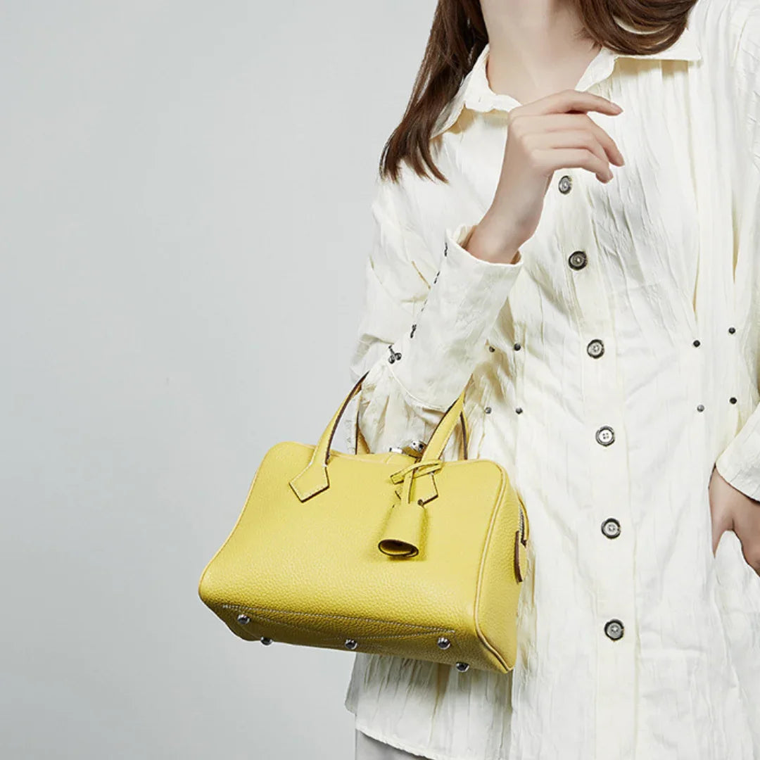 Woman in a white textured shirt holding a yellow leather handbag with silver feet
