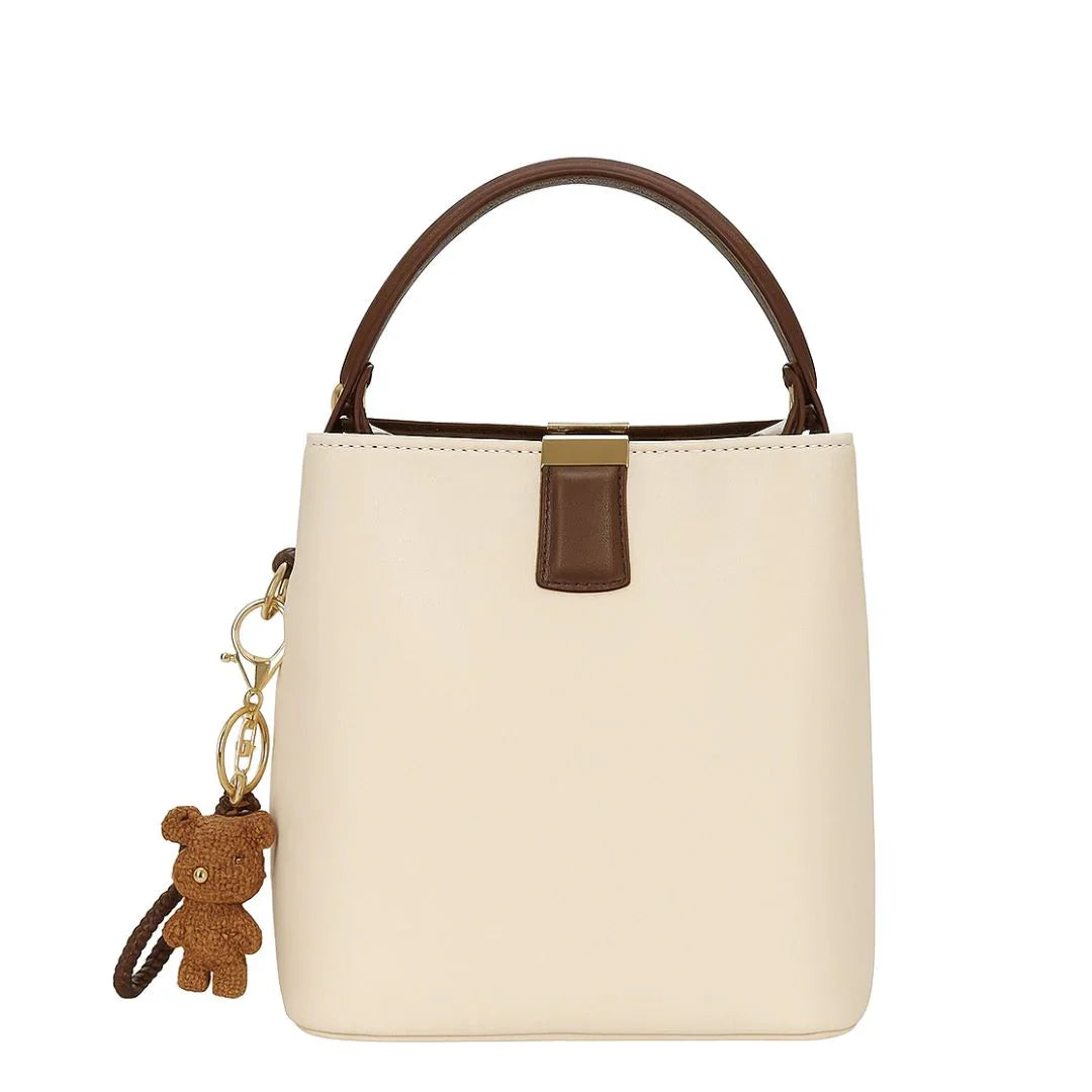 Cream bucket handbag with brown handle and teddy bear keychain accessory