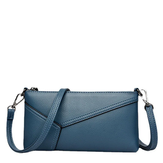 Blue faux leather crossbody bag with embossed texture and detachable strap on white background