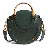 Round green leather handbag with gold rivets and handle on white background