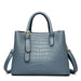 Blue crocodile pattern leather tote bag with top handles and shoulder strap on white background