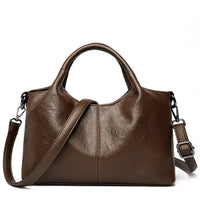 Brown leather handbag with shoulder strap and top handles on white background