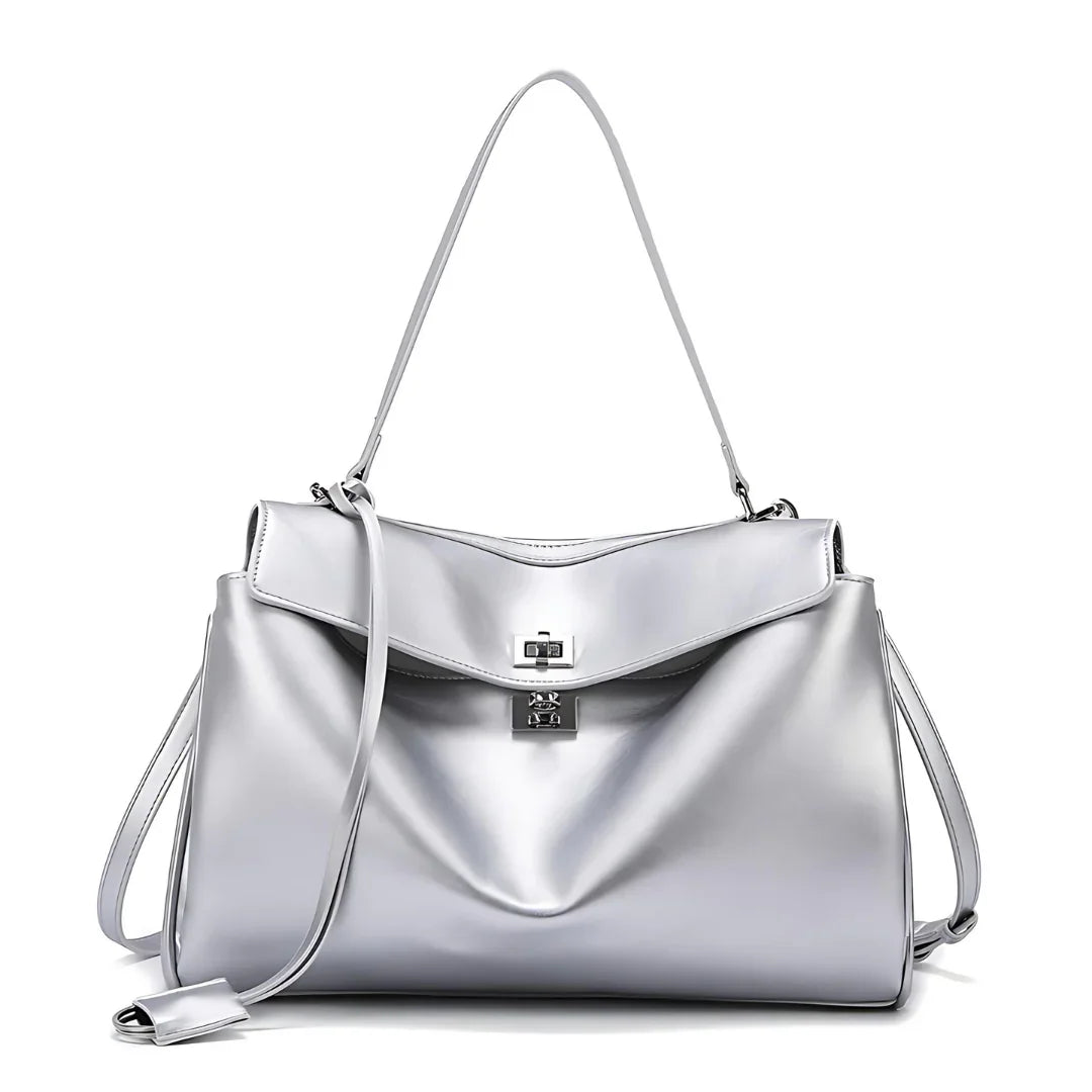 Silver leather handbag with shoulder strap, top flap, and turn-lock closure on white background.