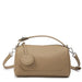 Beige leather handbag with detachable strap and round accent on white background