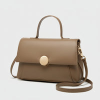 Taupe leather handbag with top handle, gold clasp, and detachable shoulder strap