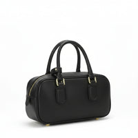 Black leather handbag with gold hardware and double handles on white background