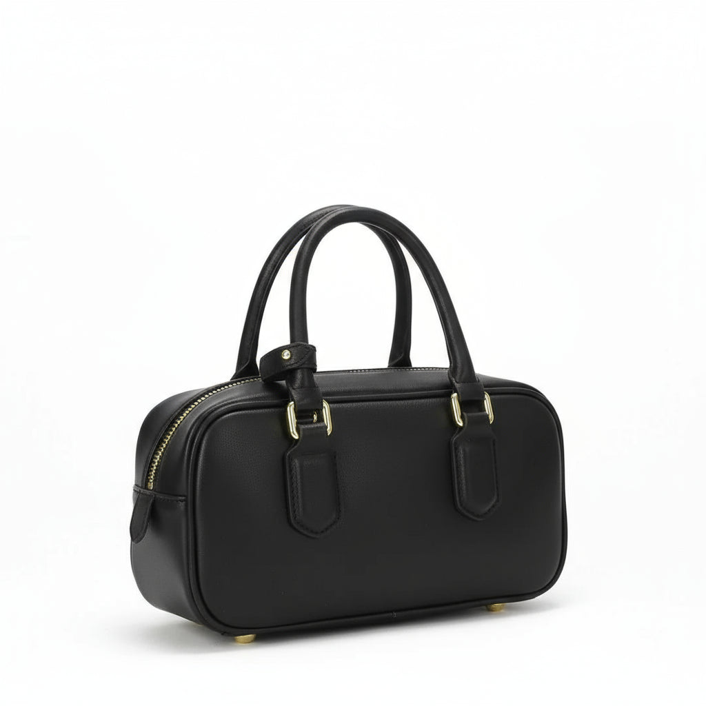 Black leather handbag with gold hardware and double handles on white background